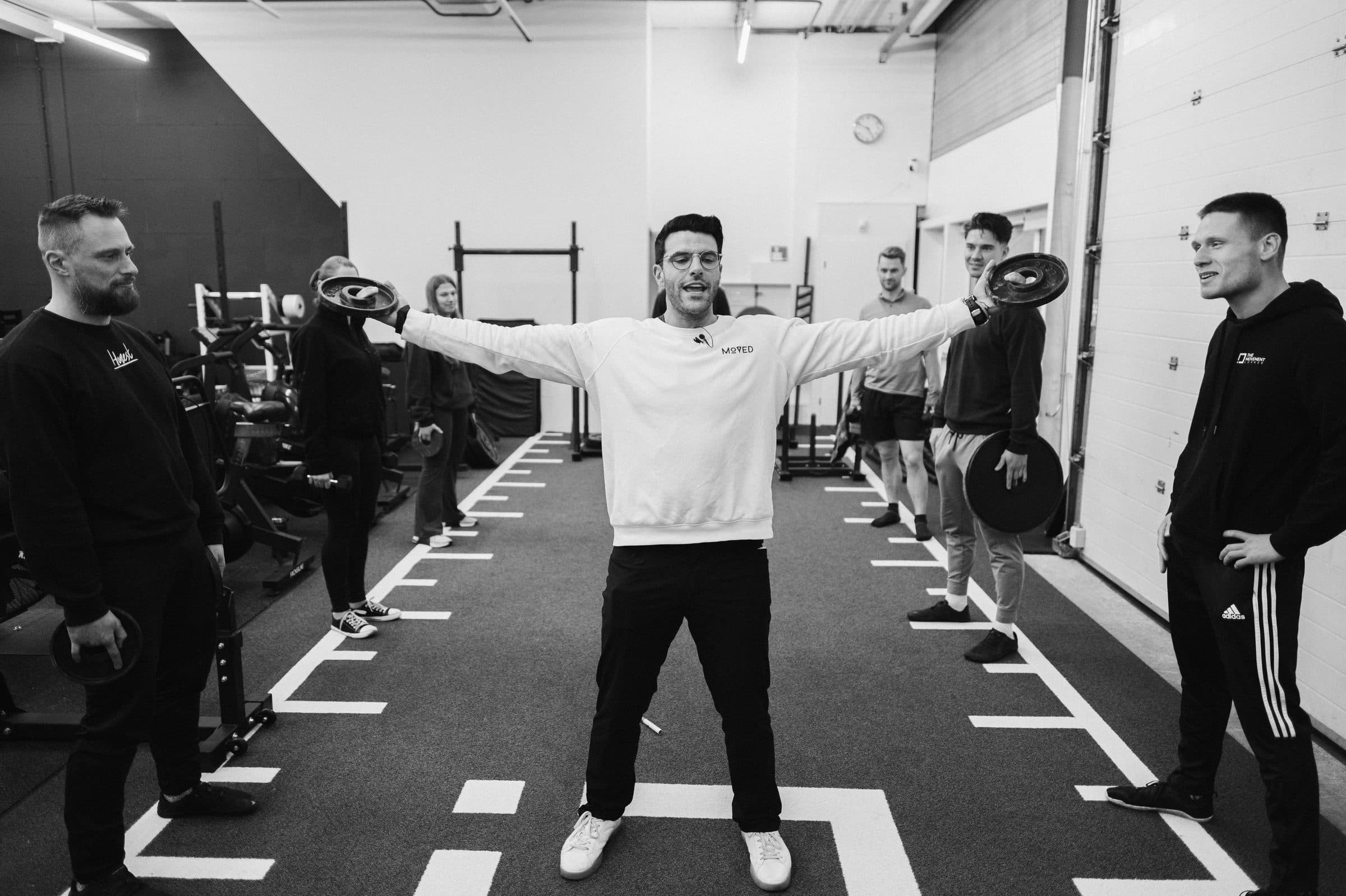 Richard Aceves standing arms outstretched at the center of a symmetrical group of coaches