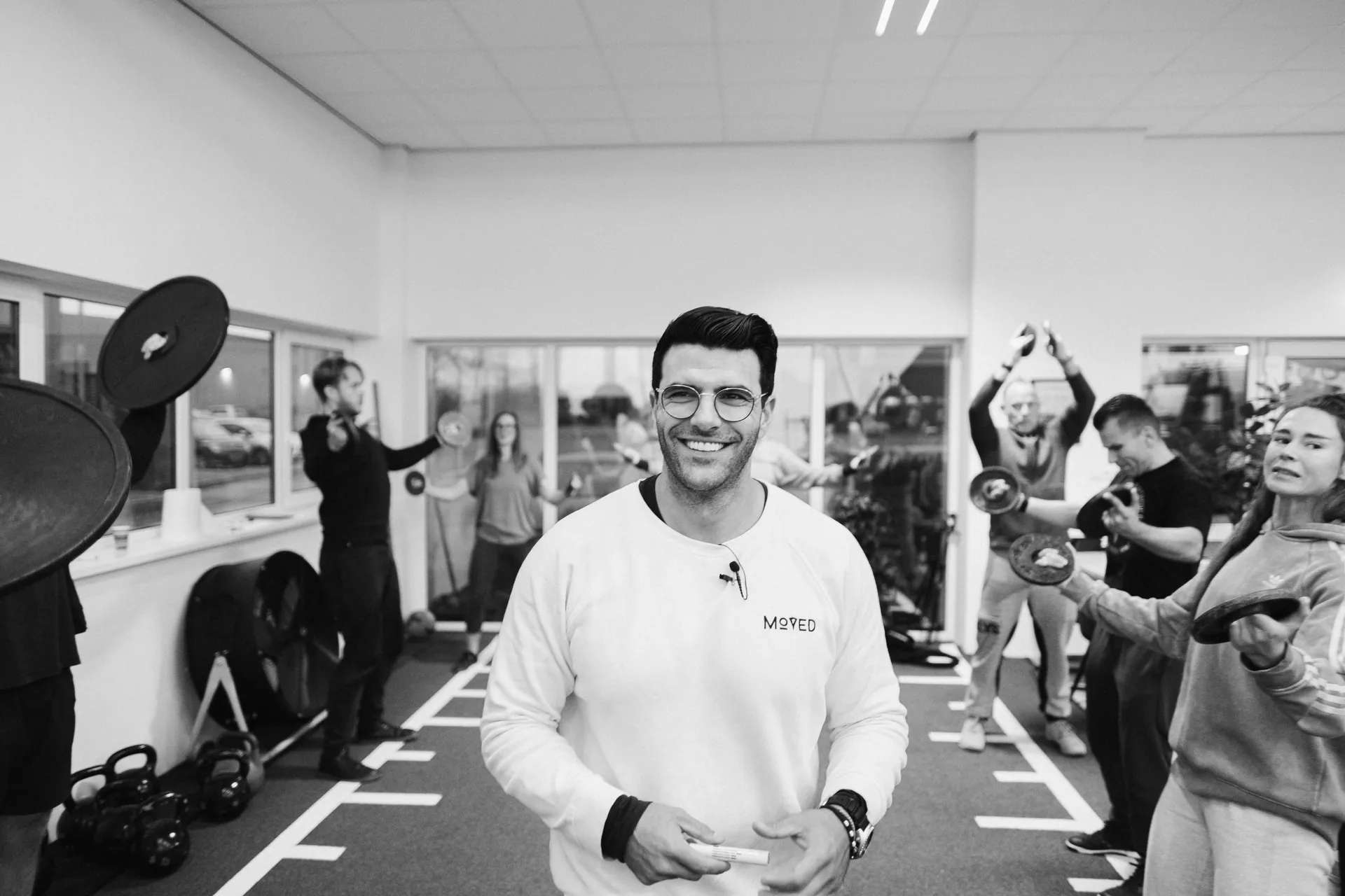 Richard Aceves smiling directly at the camera, coaches training in the background