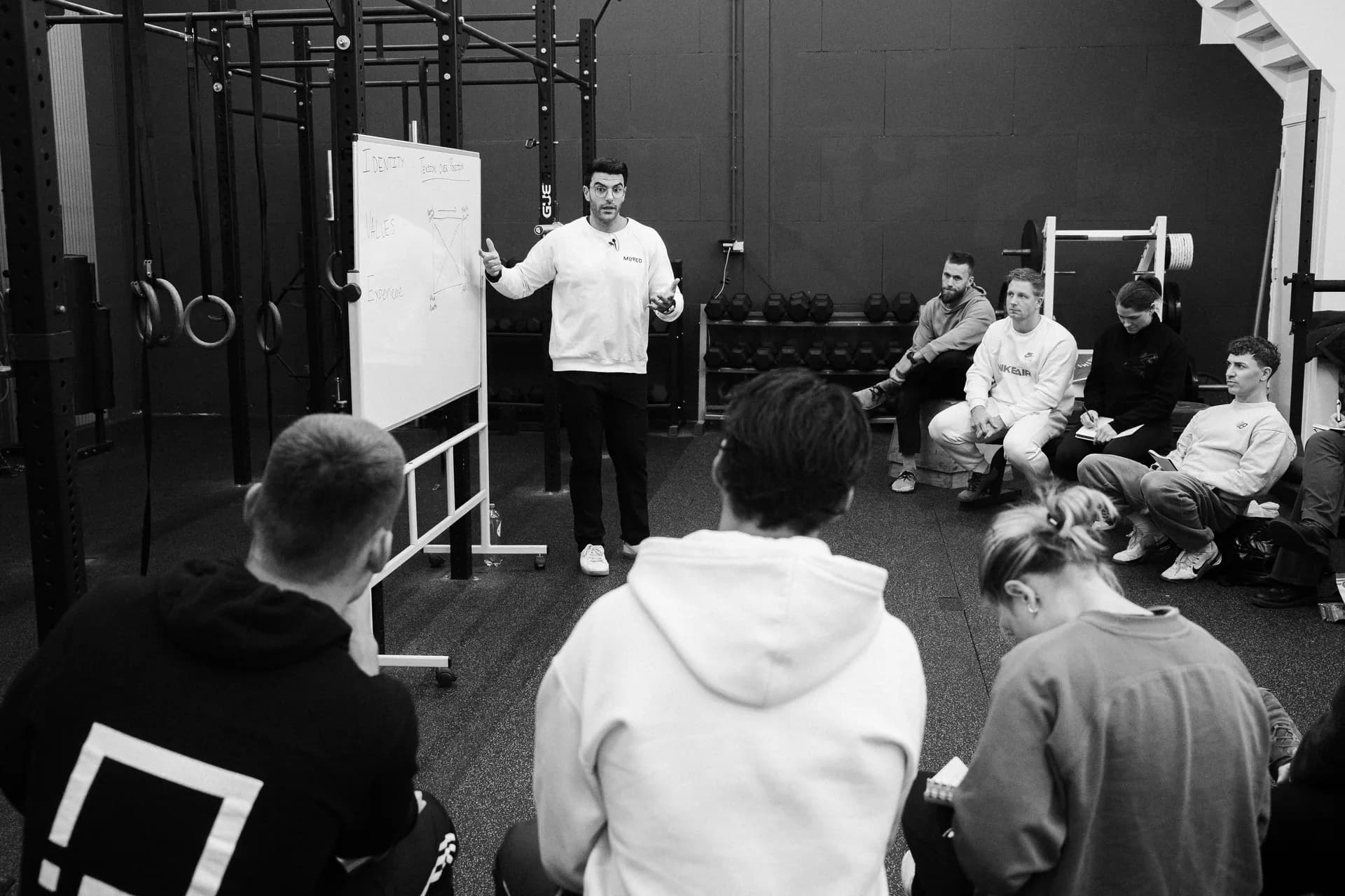 Richard Aceves teaching at a whiteboard in front of a seated semicircle of coaches