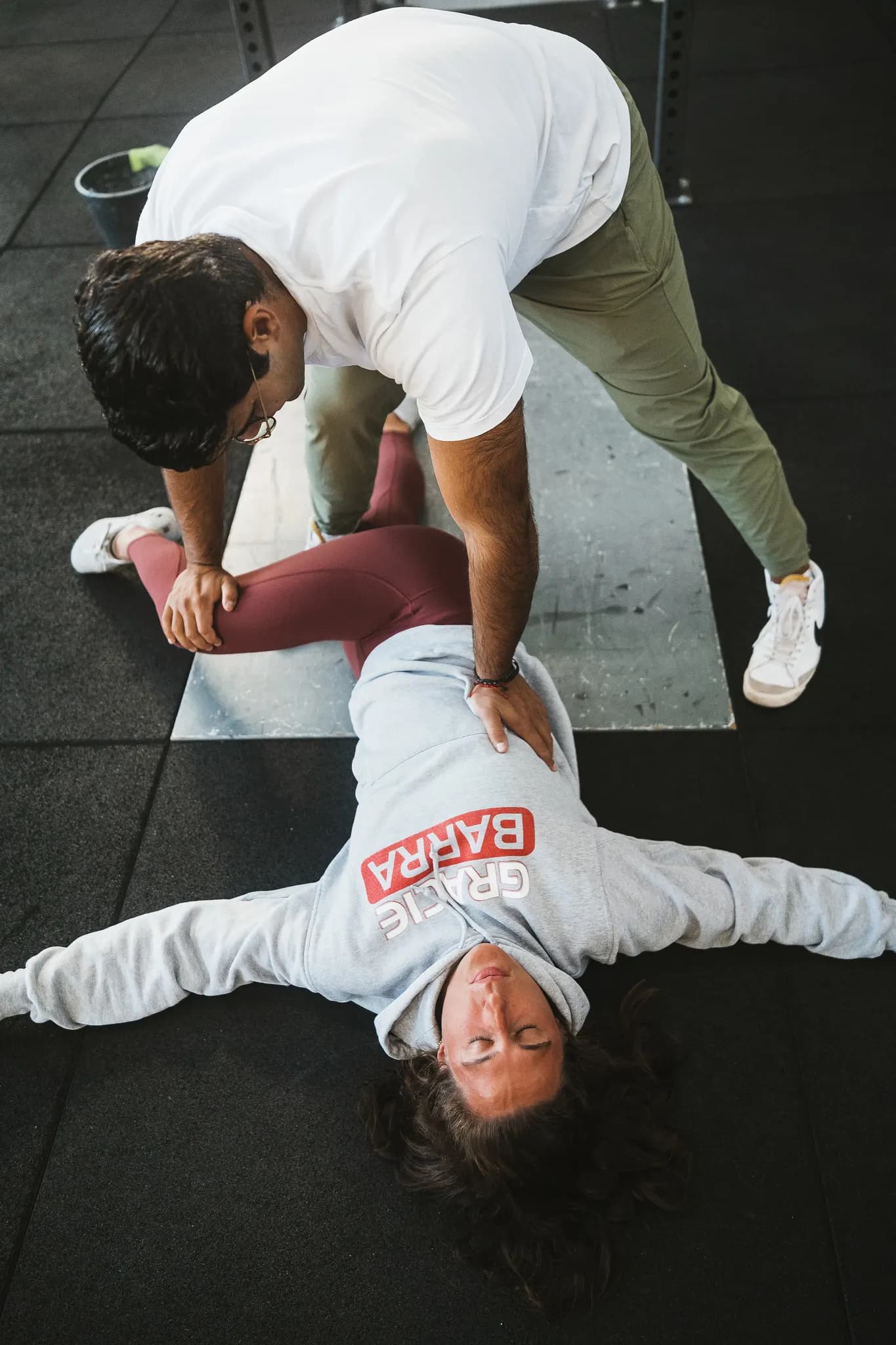 Richard Aceves coaching a client through a loaded carry, hand on the torso to cue how the body holds the weight