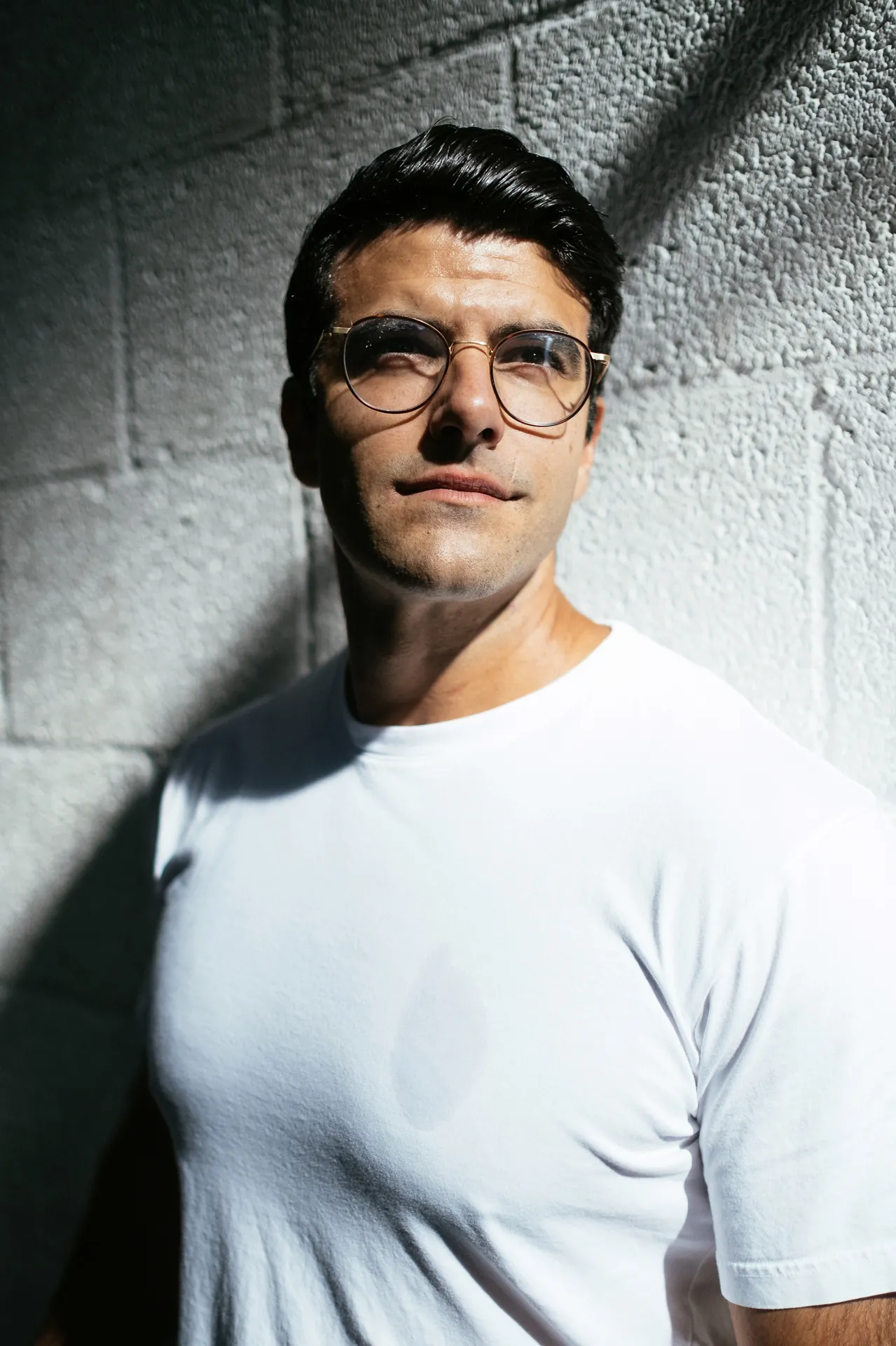 Richard Aceves in dramatic side light against a concrete wall