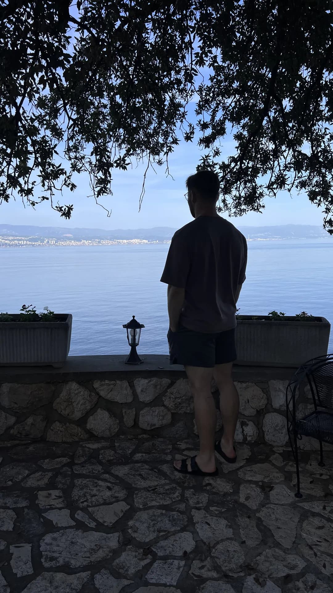 Richard Aceves standing on a stone terrace looking out over a lake toward distant mountains