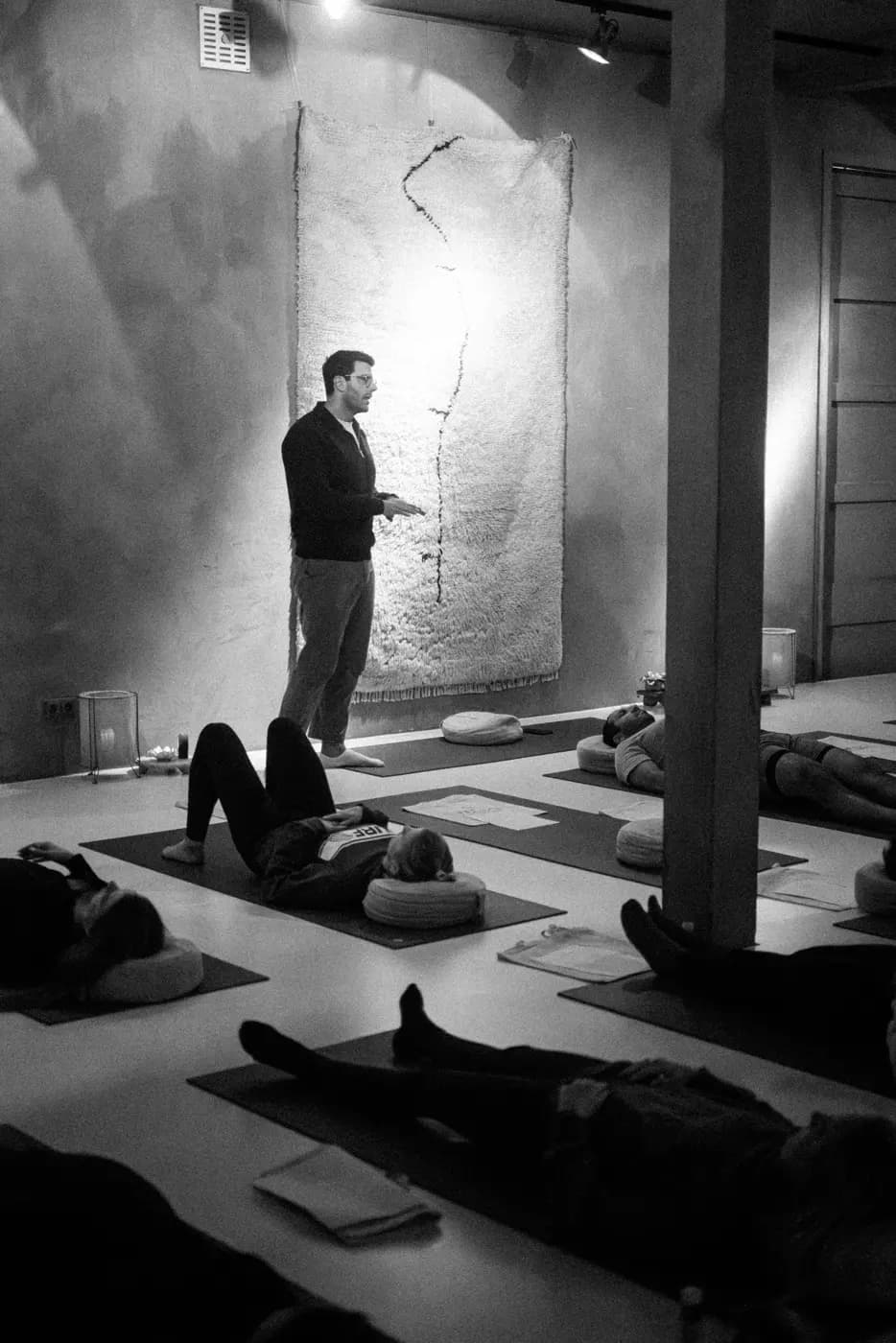 Richard Aceves standing and teaching while participants lie on mats during a guided Swami practice
